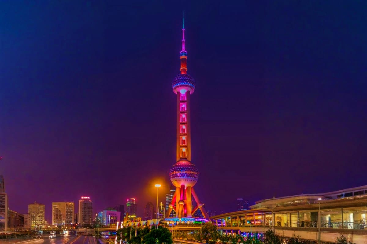 Oriental Pearl Tower illuminated in pink and orange neon lights at night in Shanghai, China