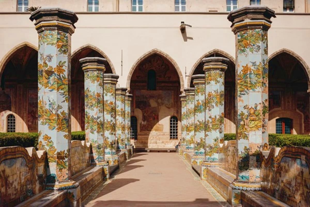 Historic Islamic courtyard with ornate painted tile columns, arched doorways, and traditional architecture in Uzbekistan