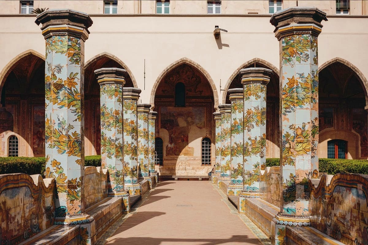 Ornate courtyard with hand-painted ceramic columns featuring yellow floral designs, arched doorways, and traditional Islamic 