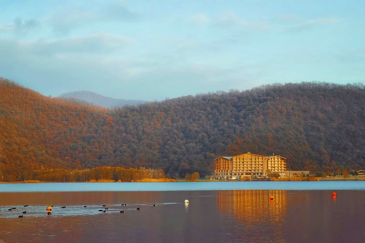 Lakeside resort hotel in Gabala surrounded by forested mountains during autumn with water birds on the lake