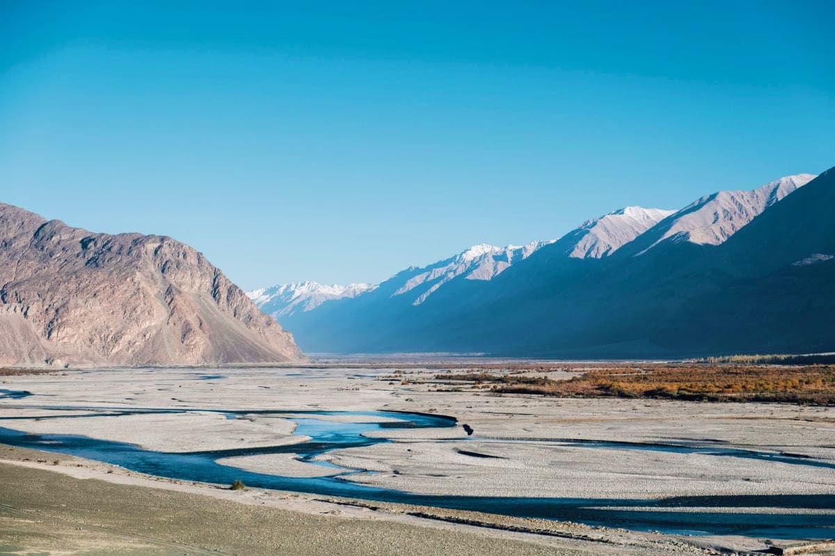 Snow-capped mountains and braided blue river in Ladakh's high-altitude desert valley landscape