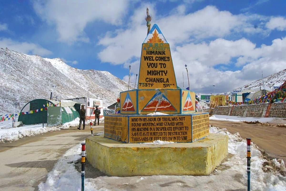 Welcome sign at Changla pass in the Himalayas with snow-covered mountains and altitude marker at 5,328 feet