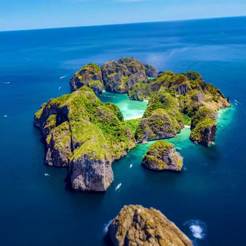 Aerial view of turquoise lagoon surrounded by lush green limestone cliffs and emerald waters in Thailand