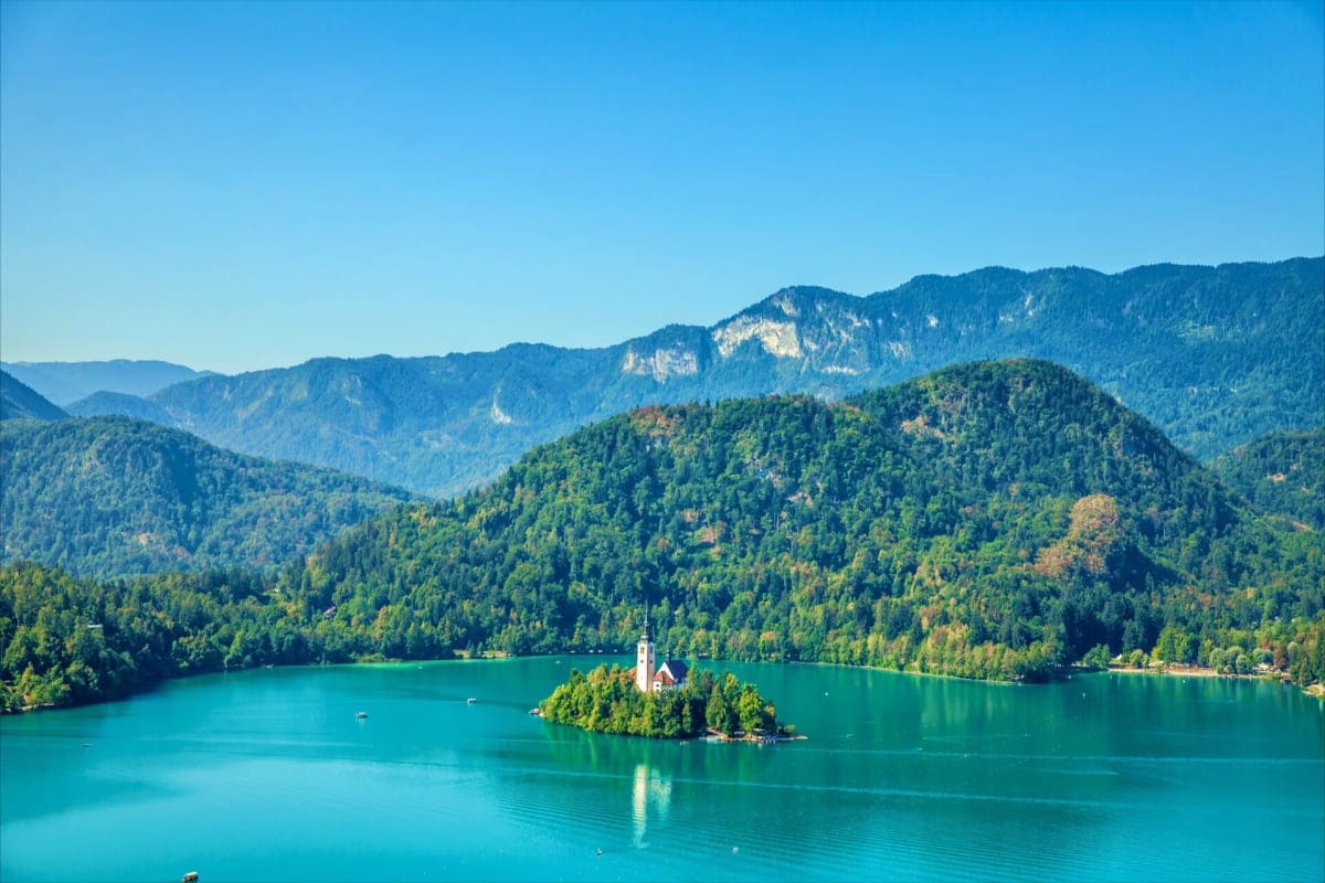 Lake Bled with Church of the Assumption on island, surrounded by forested mountains and turquoise water in Slovenia