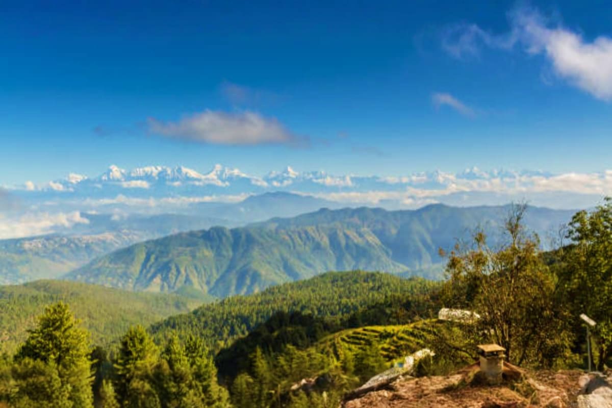 Panoramic view of snow-capped Himalayan mountains with forested valleys and green hills in Nainital region, Uttarakhand