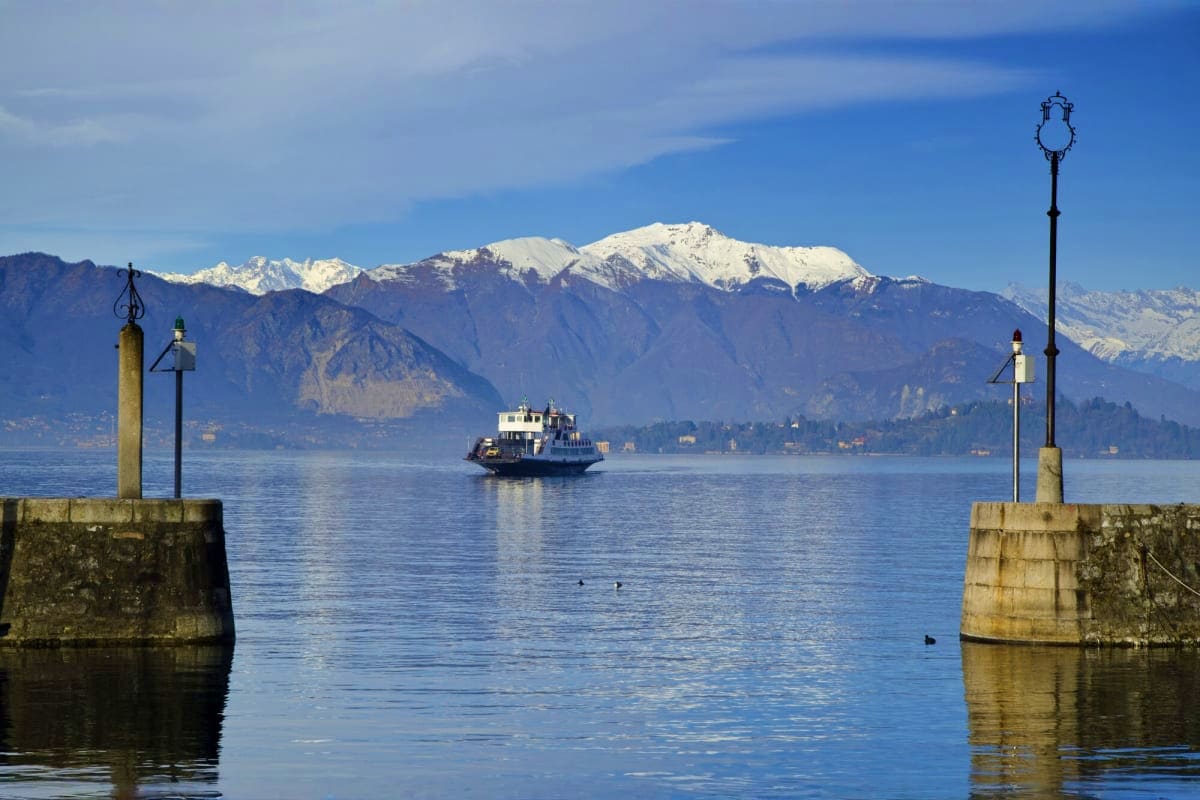 Ferry boat crossing Lake Naini with snow-capped Himalayan mountains and lakeside town in background, Nainital