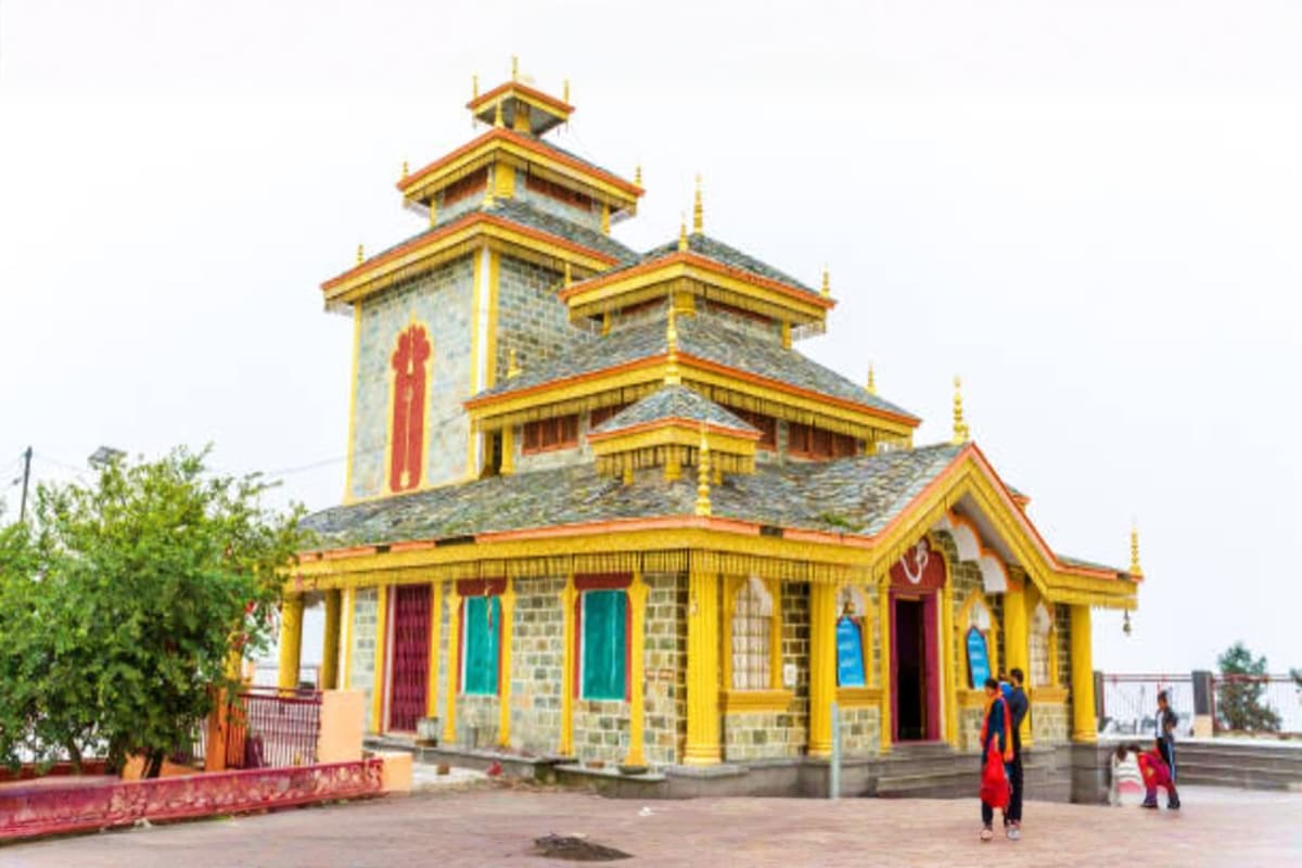 Buddhist temple with golden roofs and yellow columns in Mussoorie hill station, featuring ornate spires and colorful doors