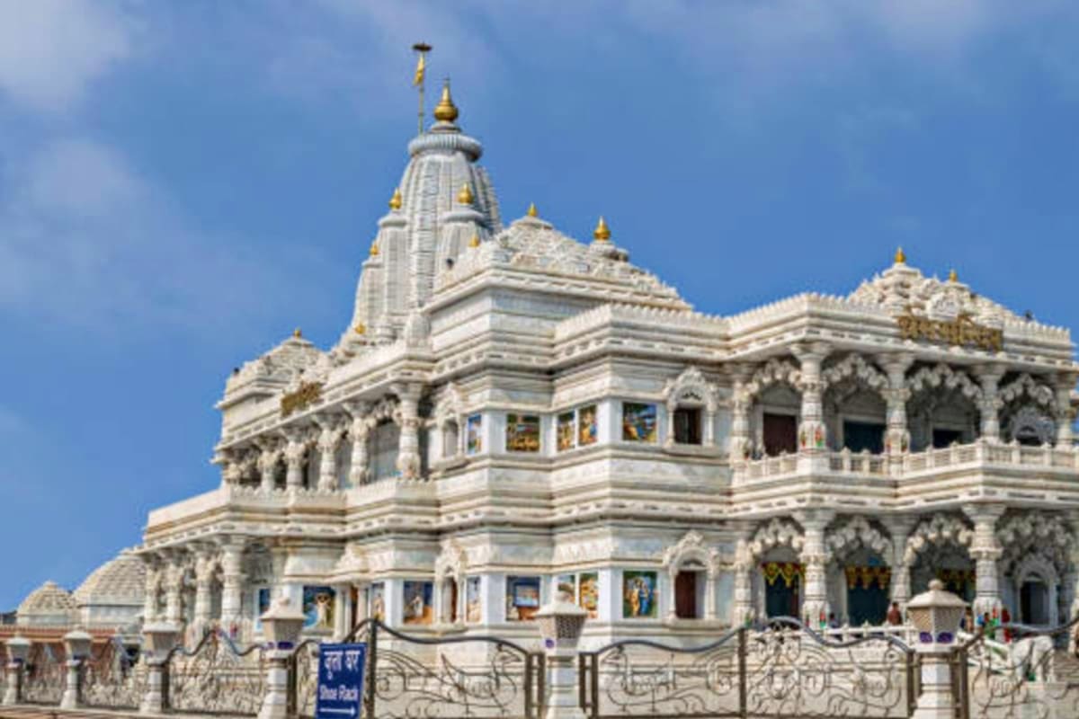 White marble Hindu temple with ornate domes and gold finials, traditional Indian religious architecture in Mathura