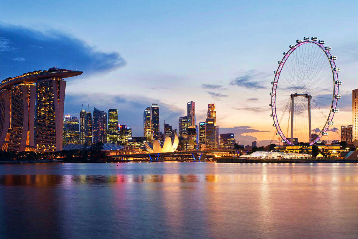 Singapore Cruise Holidays Singapore skyline at twilight featuring Marina Bay Sands, illuminated skyscrapers, and the Singapore Flyer observation wheel
