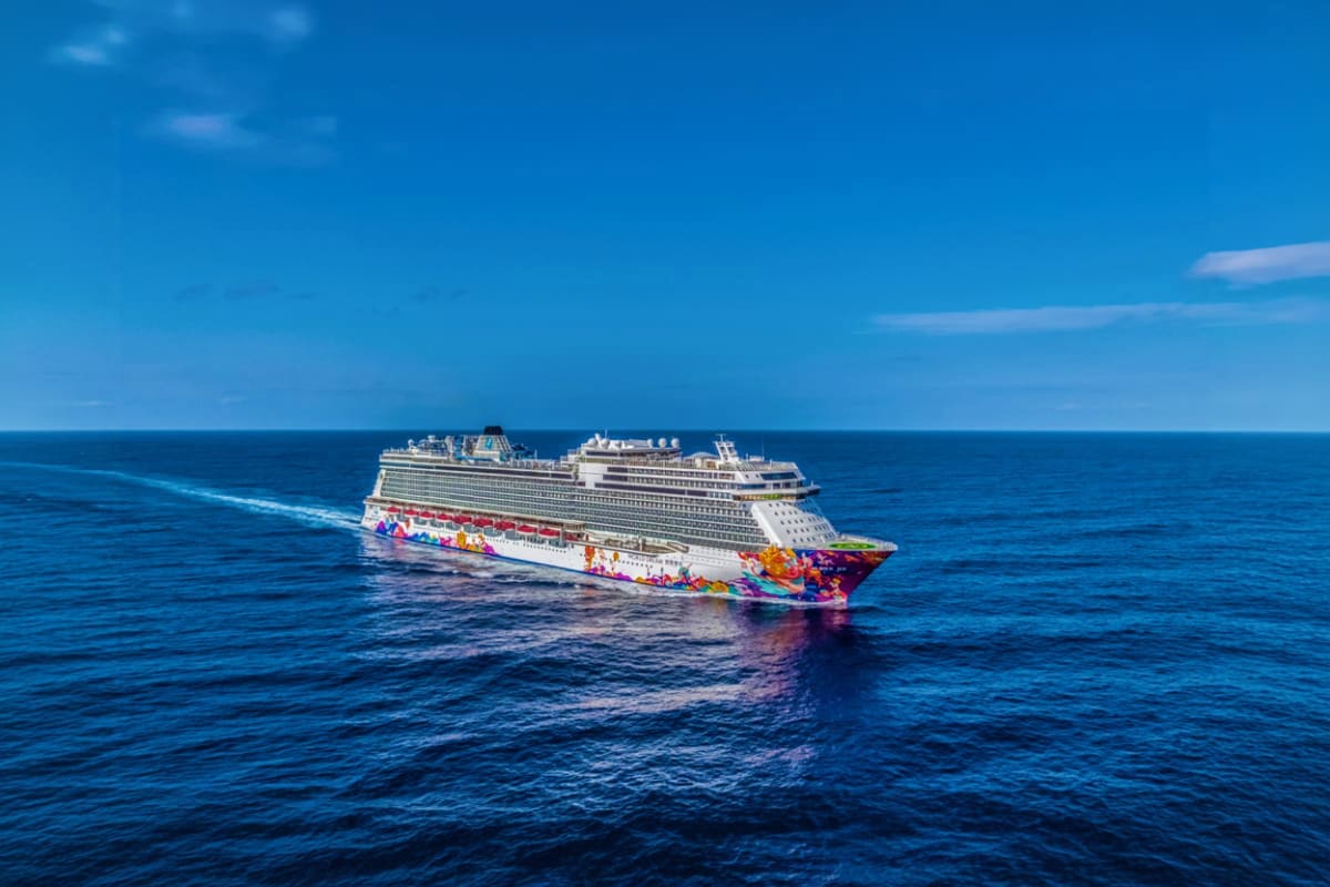 Large colorful cruise ship sailing on blue ocean waters under clear sky