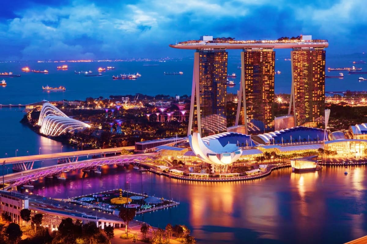 Marina Bay Sands hotel and Gardens by the Bay at twilight in Singapore, with illuminated towers and waterfront views