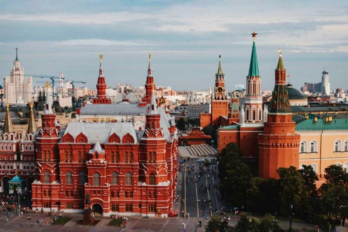 Moscow Kremlin complex with Red Square, featuring iconic red brick walls, ornate towers with golden cupolas, and historic arc
