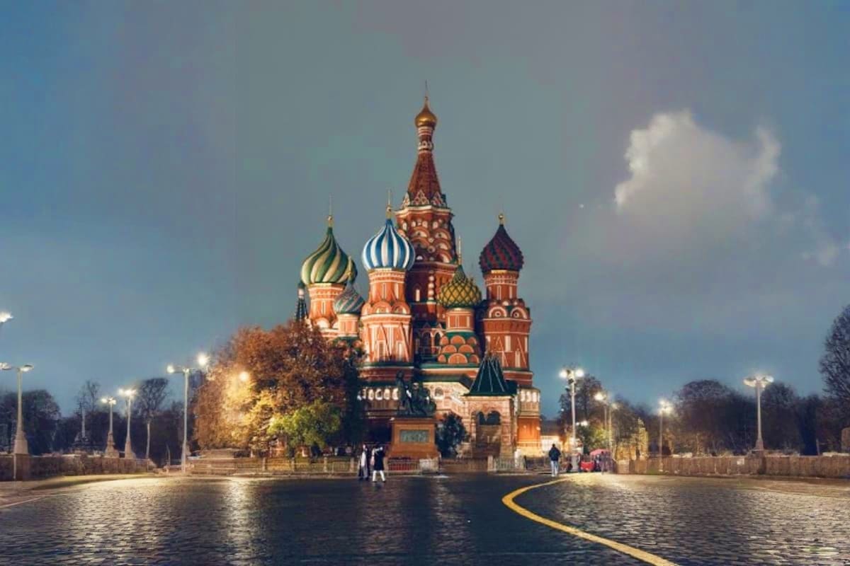 Russian Orthodox cathedral with ornate onion domes and red brick architecture surrounded by autumn trees and street lamps
