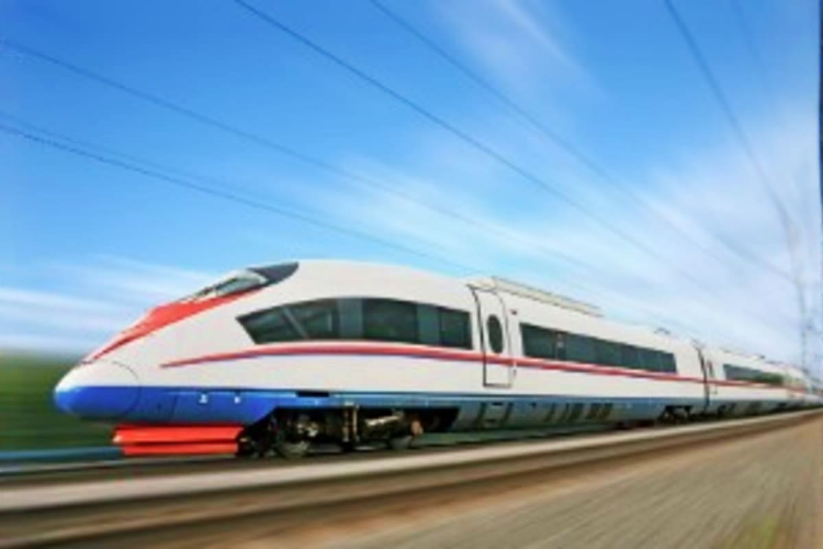 Modern high-speed train with white, red, and blue livery traveling on tracks under clear blue sky