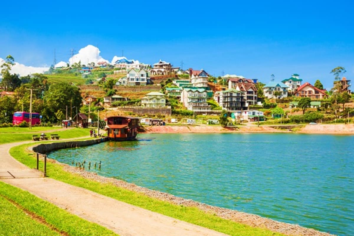 Hillside coastal town with colorful houses overlooking turquoise water, sandy beach, and traditional wooden boat at dock