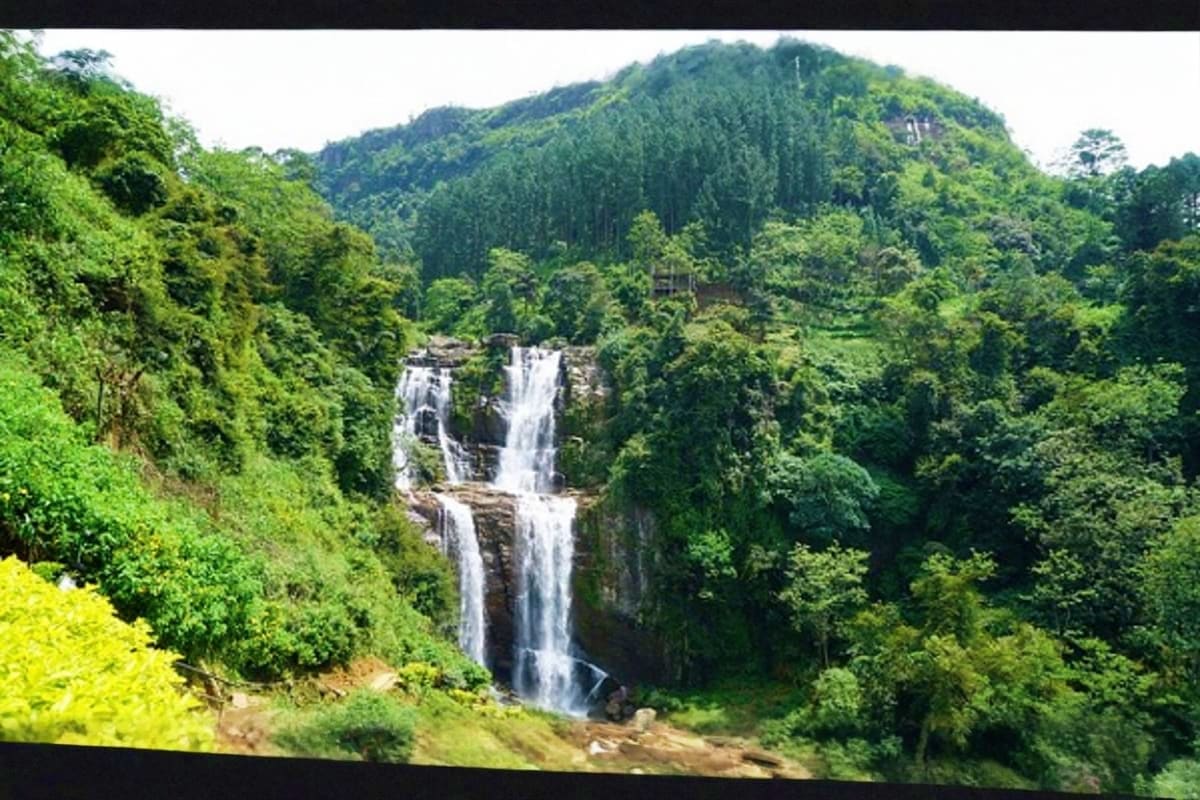 Tiered waterfall cascading through lush green forest and mountains in Sri Lanka's hill country