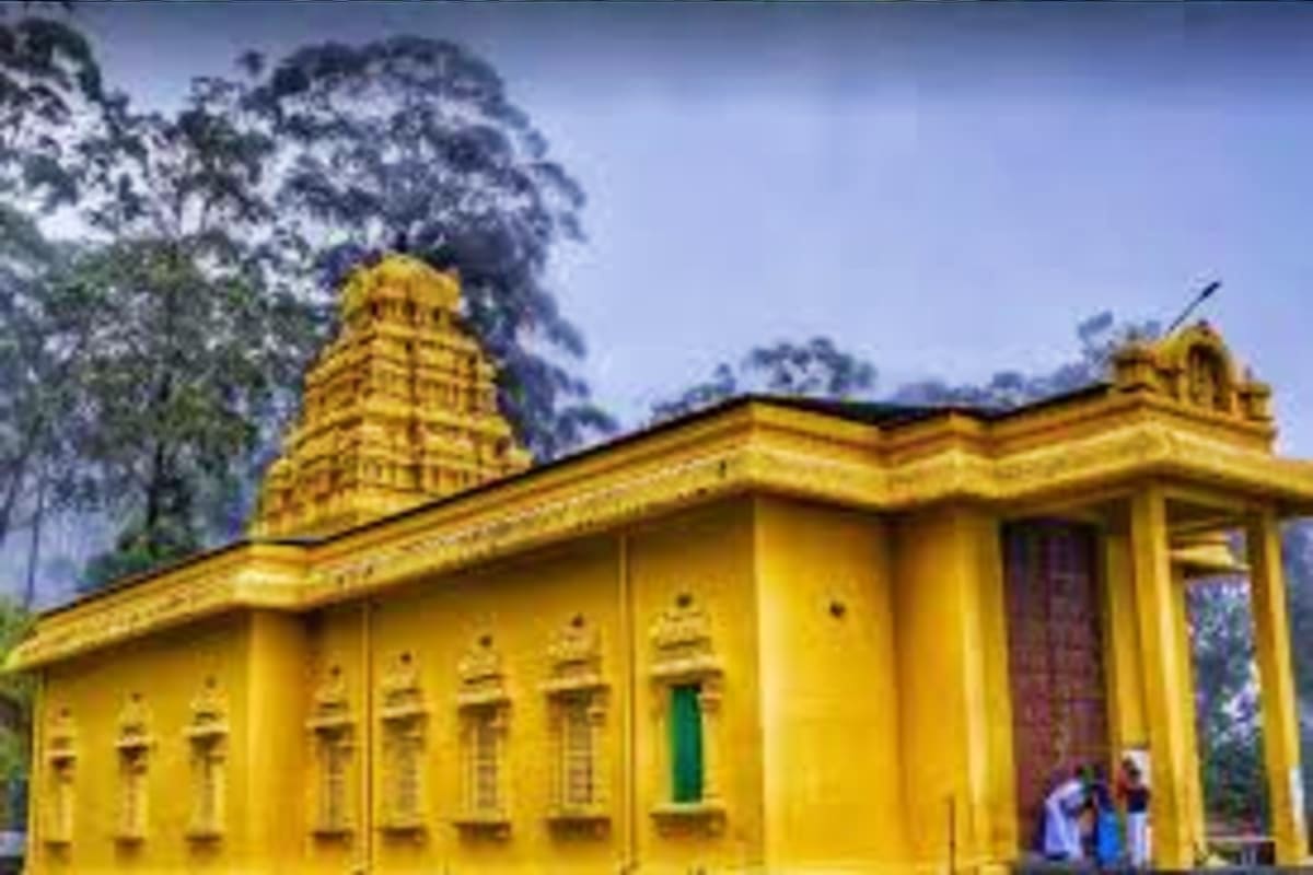 Bright yellow Hindu temple with ornate gopuram tower surrounded by snow-covered trees in mountainous Sri Lanka landscape