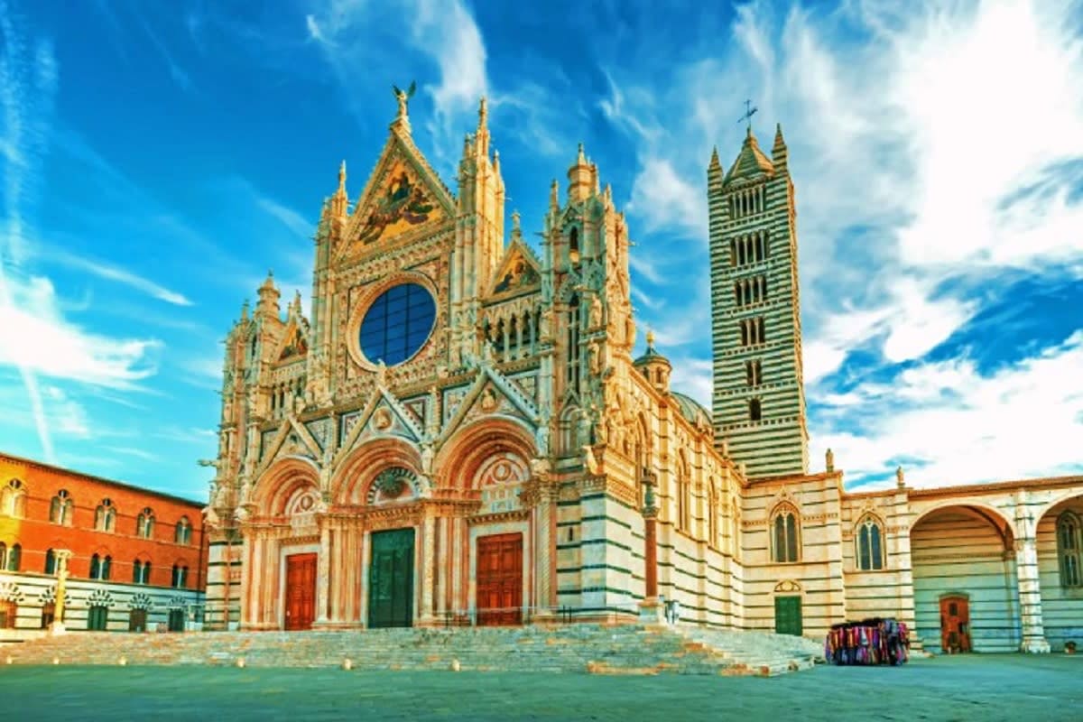 The Essential of Italy Siena Cathedral (Cattedrale di Santa Maria Assunta) with ornate Gothic facade, rose window, and striped bell tower against bl