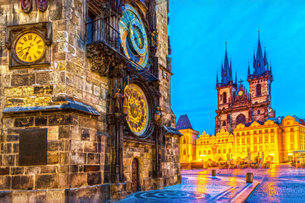 Old Town Square in Prague at twilight with illuminated historic clock tower and Church of Our Lady before Tyn