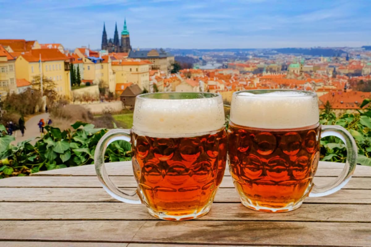 Two glasses of Czech beer with foam overlooking Prague skyline and St. Vitus Cathedral