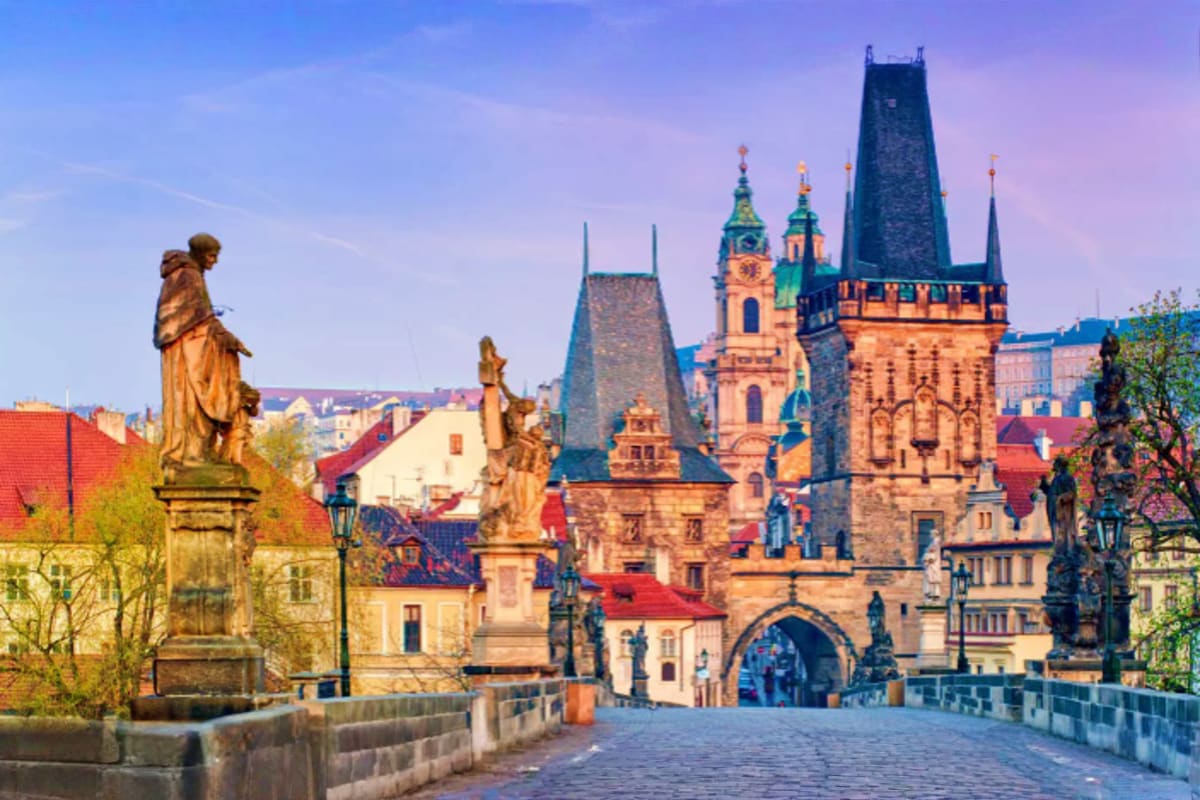 Charles Bridge in Prague with golden statues, Gothic towers, and historic architecture at sunset in Bohemia, Czech Republic