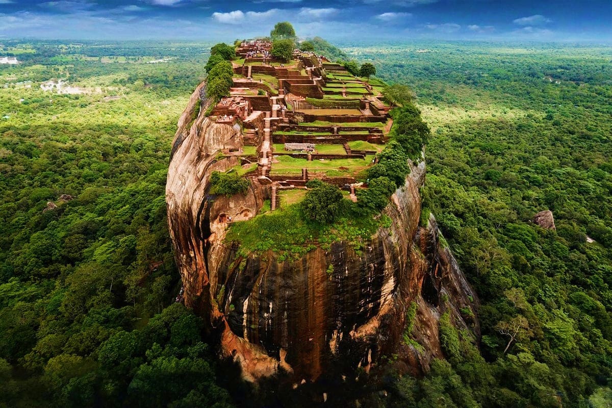Aerial view of Sigiriya rock fortress with ancient ruins and terraced gardens surrounded by lush green jungle in Sri Lanka