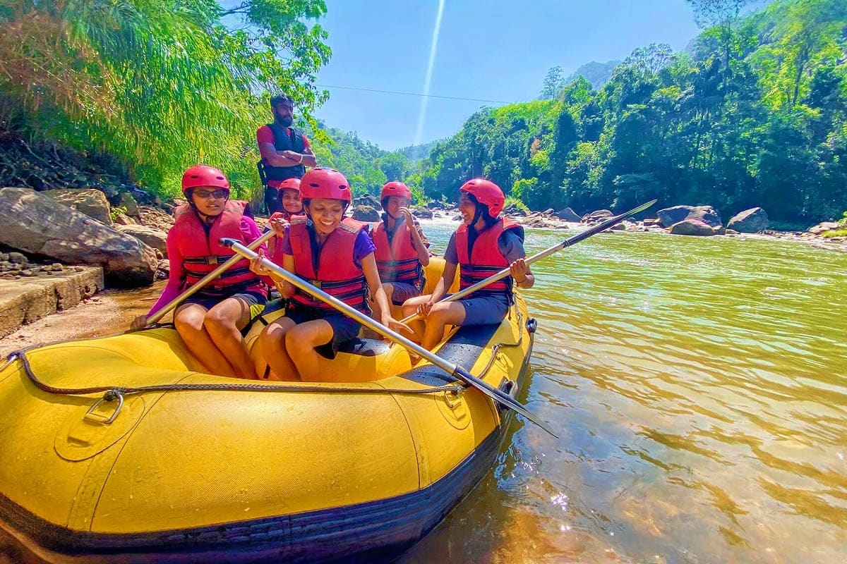 Group of tourists whitewater rafting on a river surrounded by lush green mountains and forest in Sri Lanka