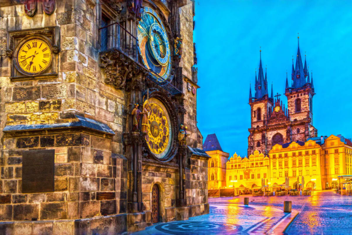 Historic astronomical clock tower and Church of Our Lady before Tyn illuminated at dusk in Prague's Old Town Square