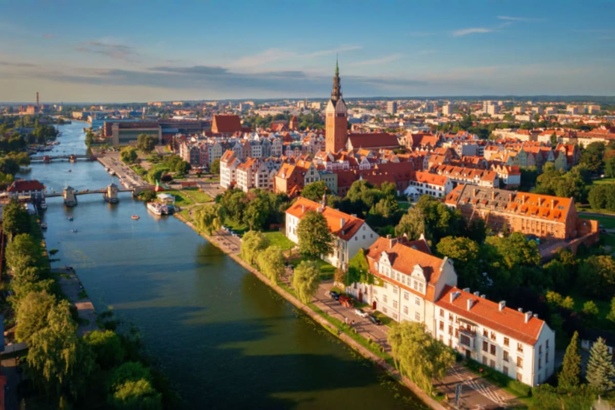 Aerial view of Greifswald, Germany showing the Oder River, historic red-roofed buildings, church spire, and riverside promena