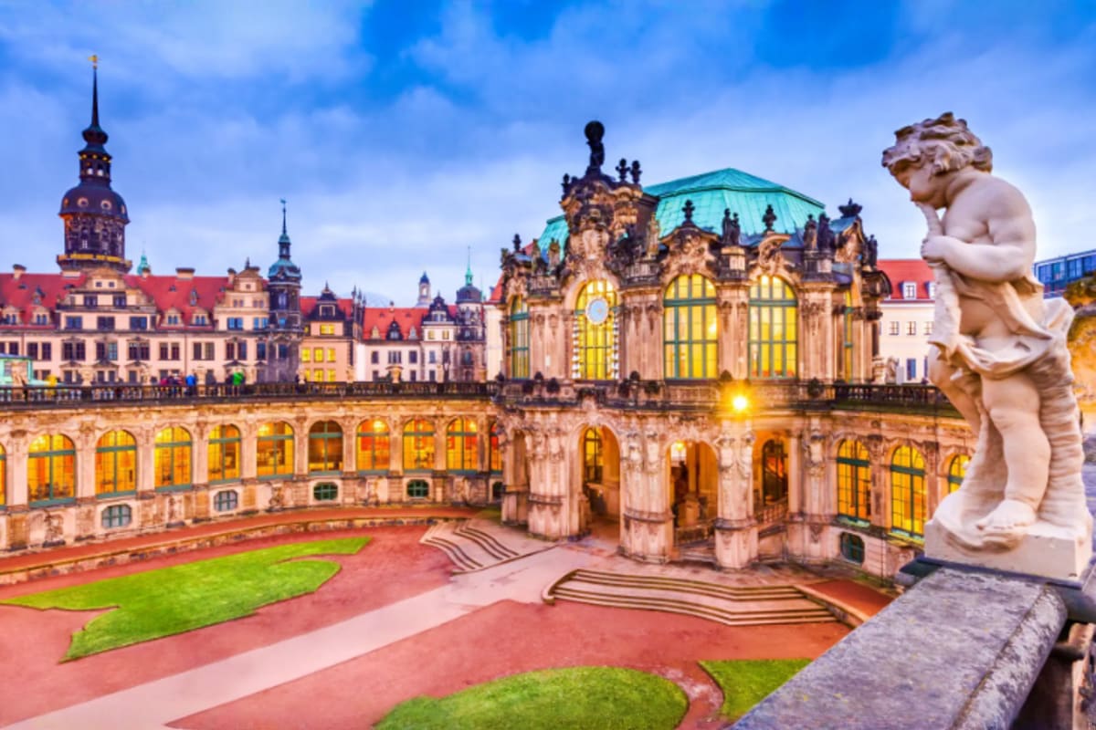 Zwinger Palace courtyard in Dresden with ornate baroque architecture, illuminated windows, manicured gardens, and classical s
