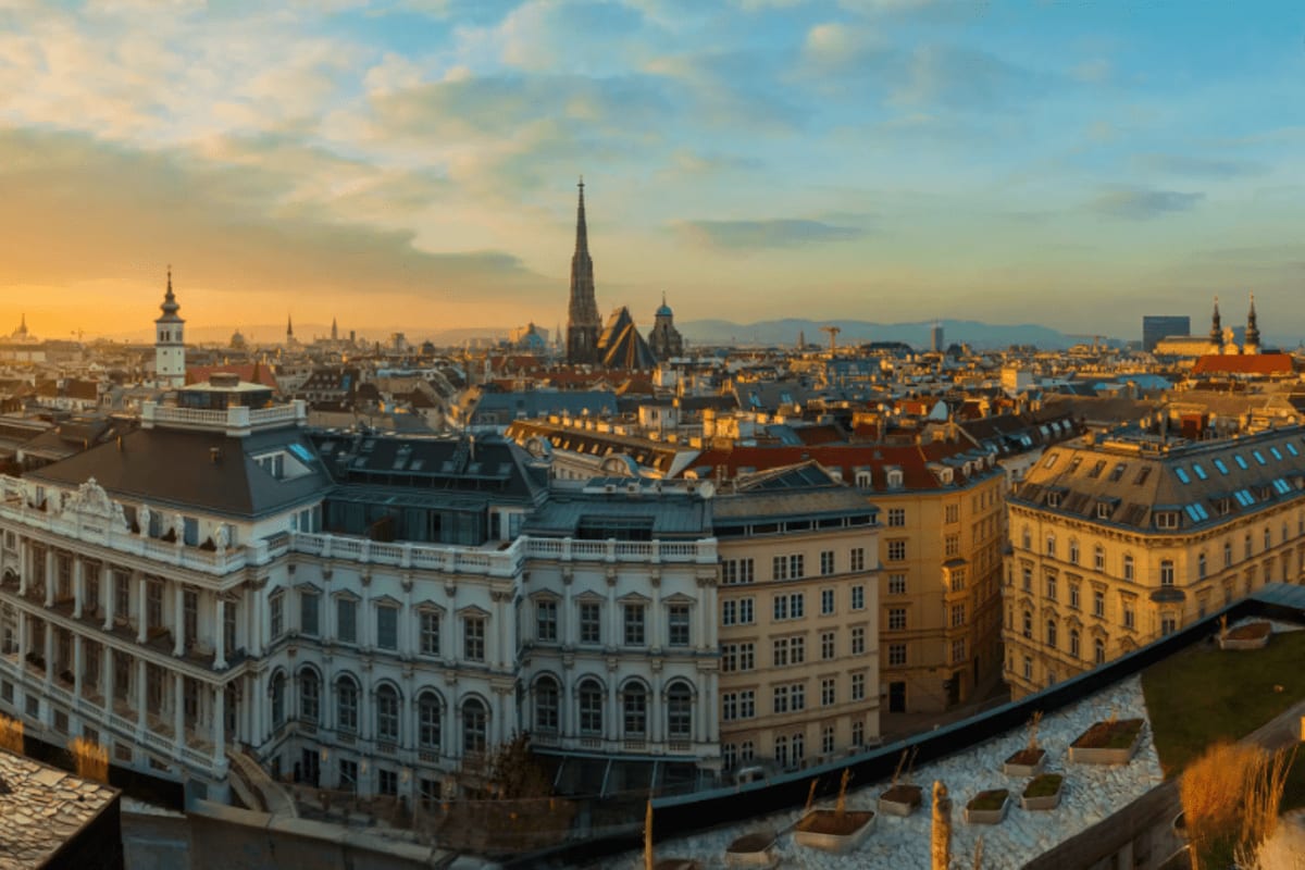 Golden hour cityscape of Vienna, Austria with historic buildings, spires, and the Danube River visible below
