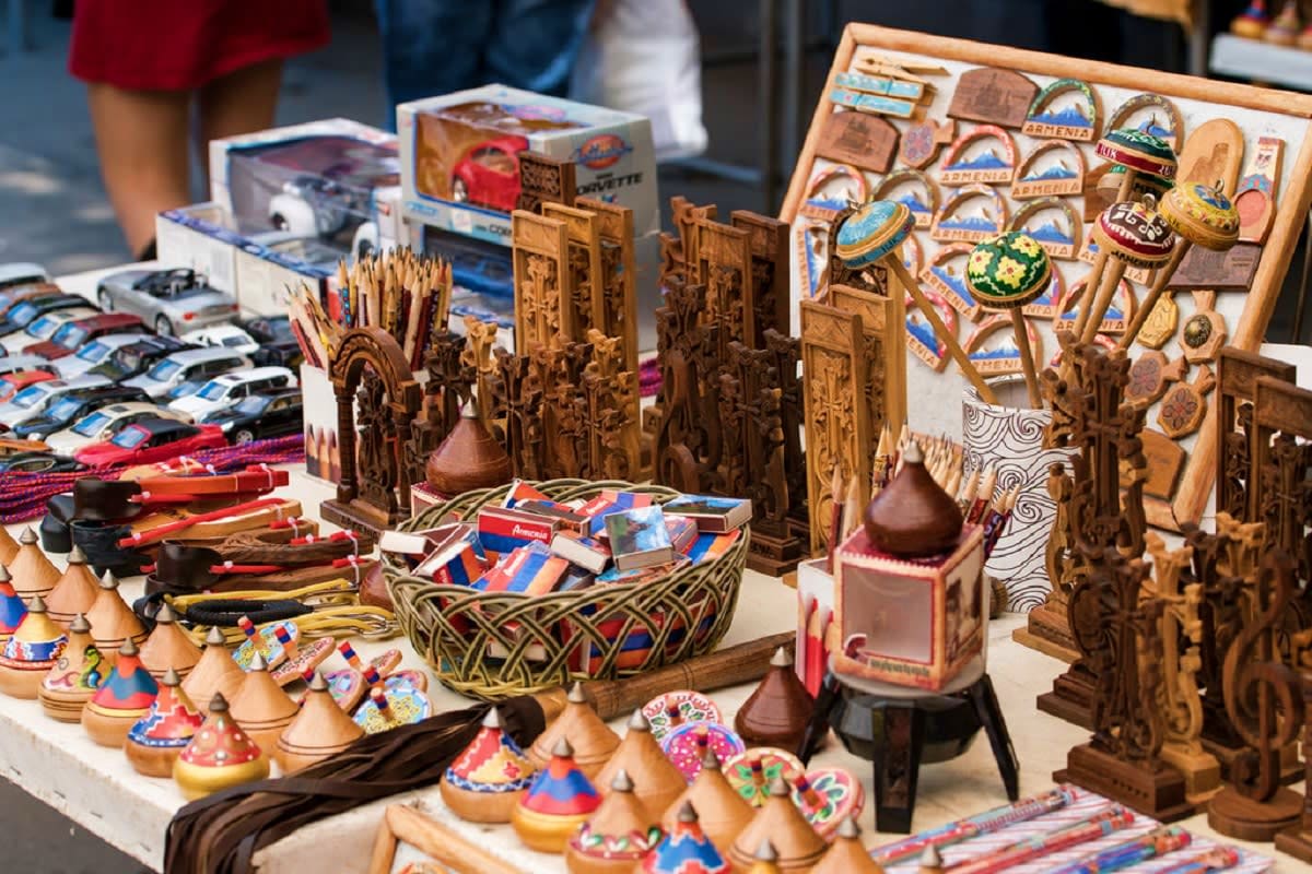 Wooden carved Armenian souvenirs and traditional crafts displayed at market stall, including decorative boxes, hats, and pain