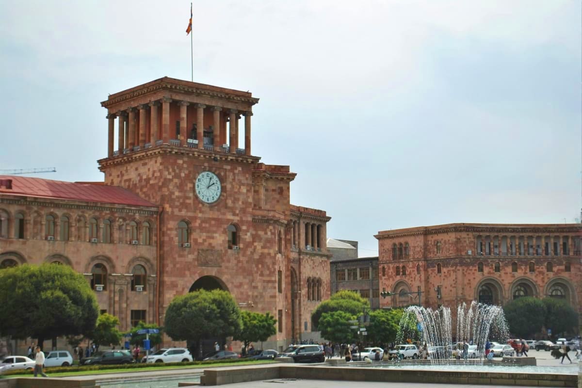 Historic red brick government building with clock tower and Armenian flag in Republic Square, Yerevan, Armenia