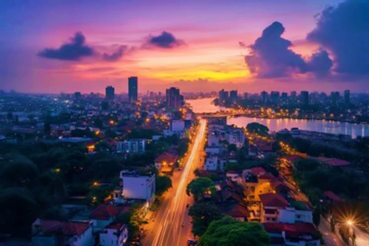 Aerial cityscape at sunset showing illuminated highway, river, and skyline with colorful sky in Sri Lanka