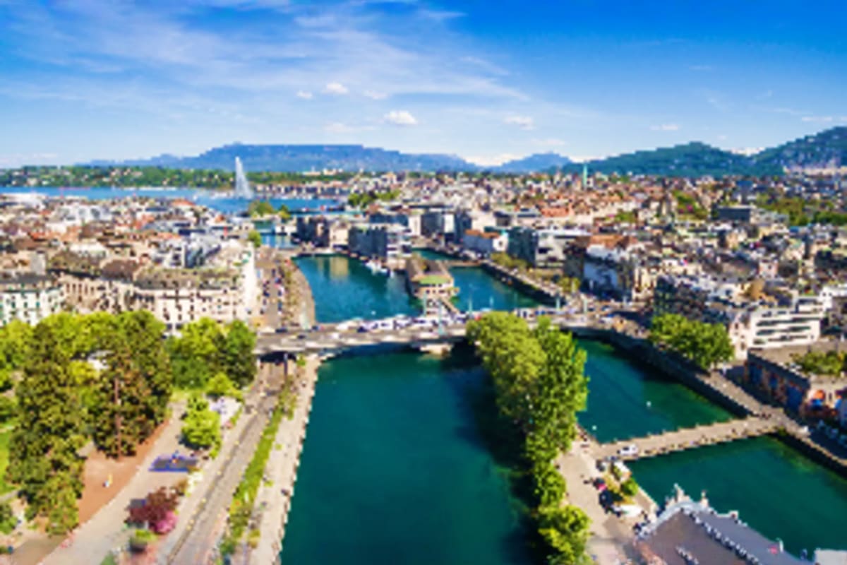Aerial view of Zurich cityscape with turquoise rivers, bridges, surrounding mountains and lakefront under blue sky