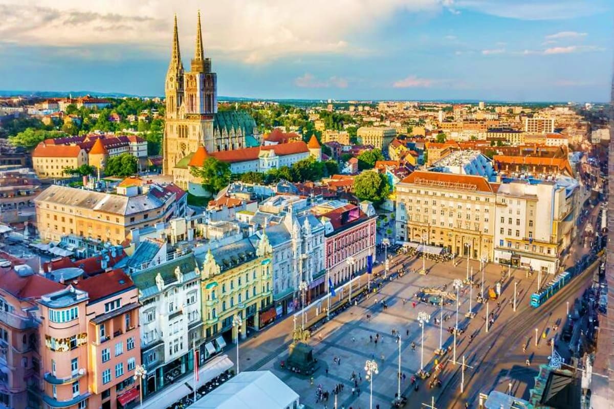 Aerial view of Zagreb city center featuring Cathedral with twin golden spires, colorful historic buildings, and town square w
