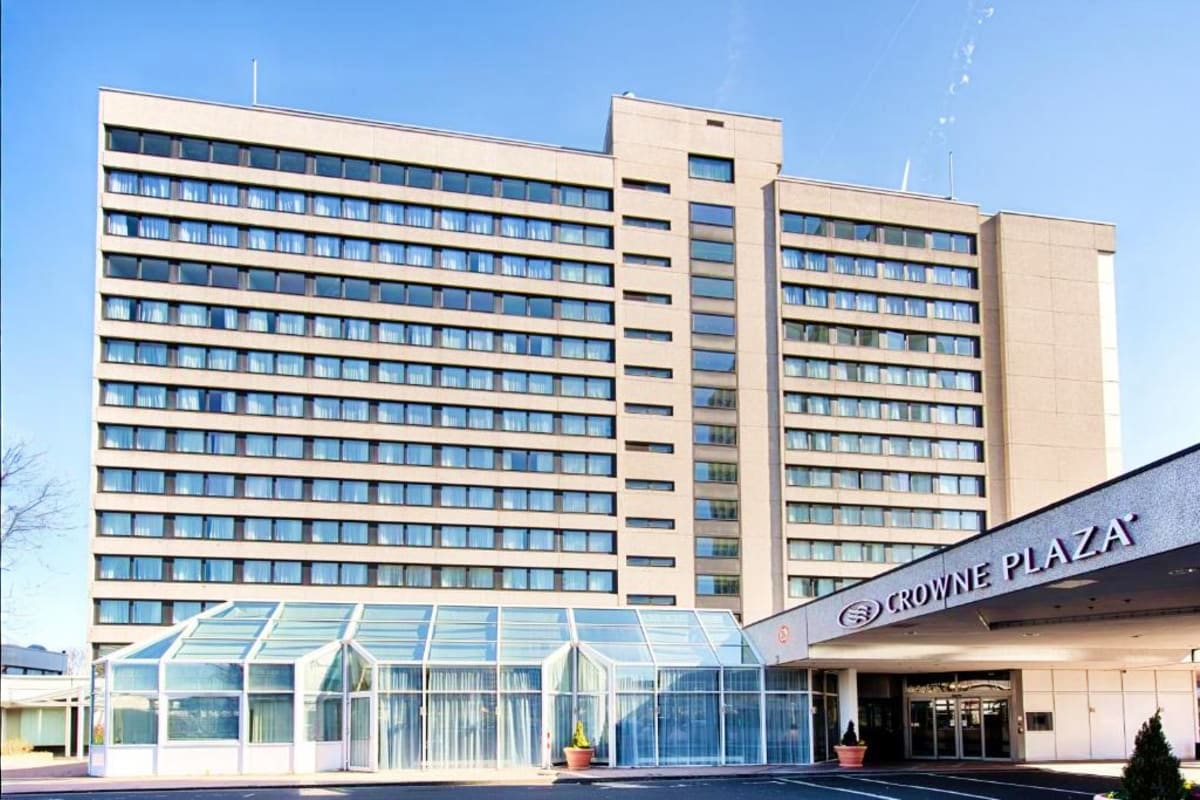 Crowne Plaza Hotel exterior, modern multi-story beige building with glass entrance lobby and signage