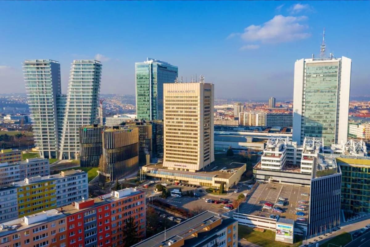 Aerial view of Frankfurt skyline showing modern skyscrapers, Panorama Hotel, and residential buildings under blue sky