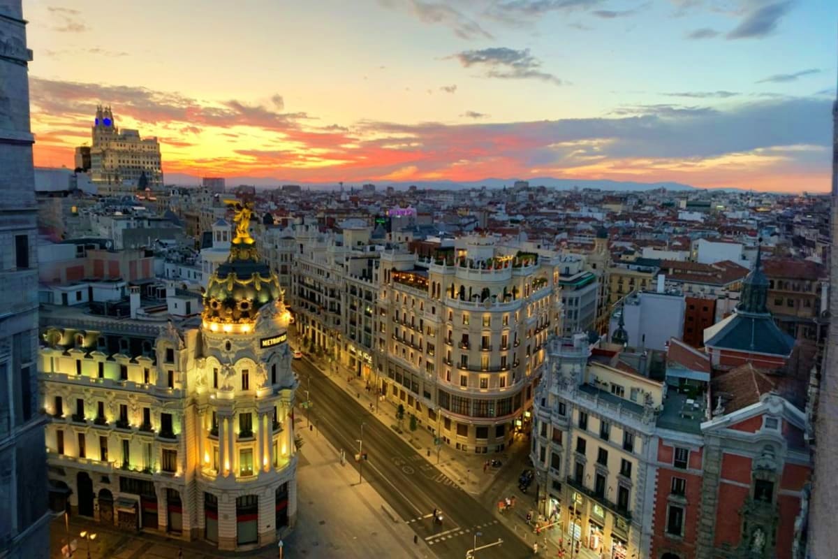 Madrid cityscape at sunset with illuminated historic buildings and golden dome church tower overlooking urban streets