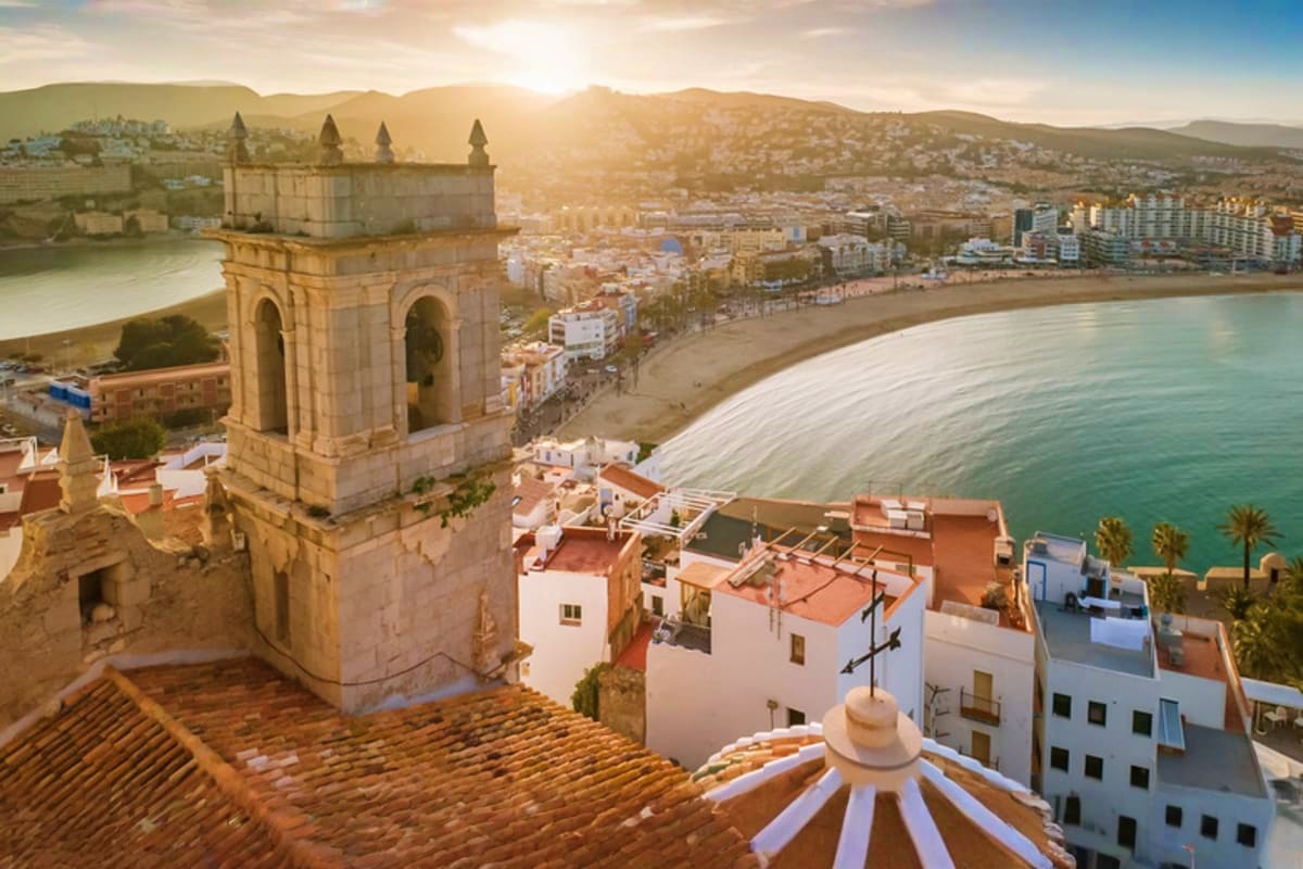 Aerial view of Peniscola Castle tower overlooking Mediterranean beach and coastal town at sunset in Spain