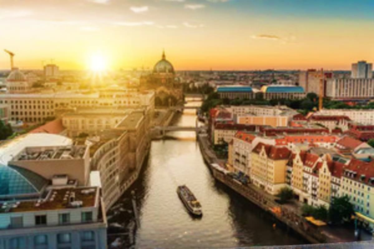 Aerial sunset view of Berlin cityscape with river canal, historic dome, colorful residential buildings, and modern architectu