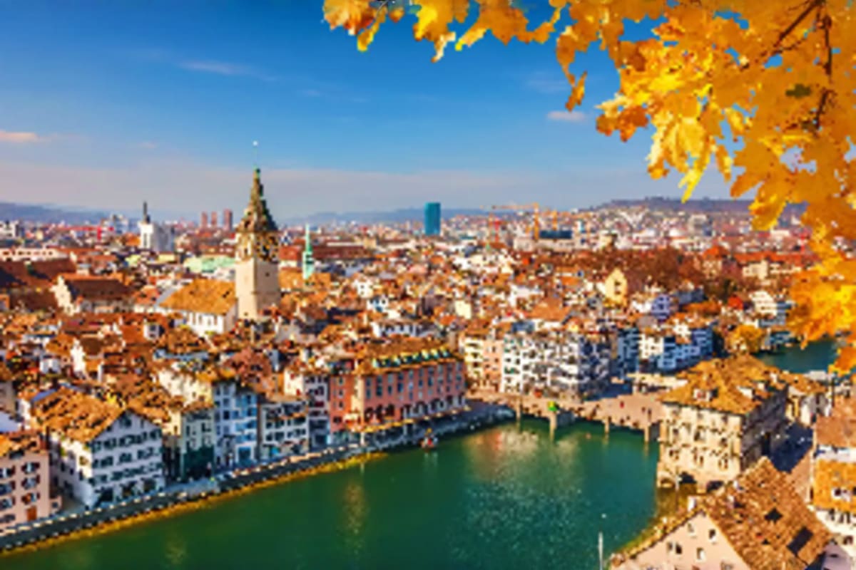 Zurich cityscape in autumn with River Limmat, historic churches, and golden foliage framing the view