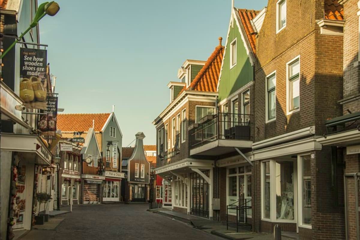 Traditional Dutch street in Amsterdam with historic brick buildings, orange-tiled roofs, and wooden shoe shop sign