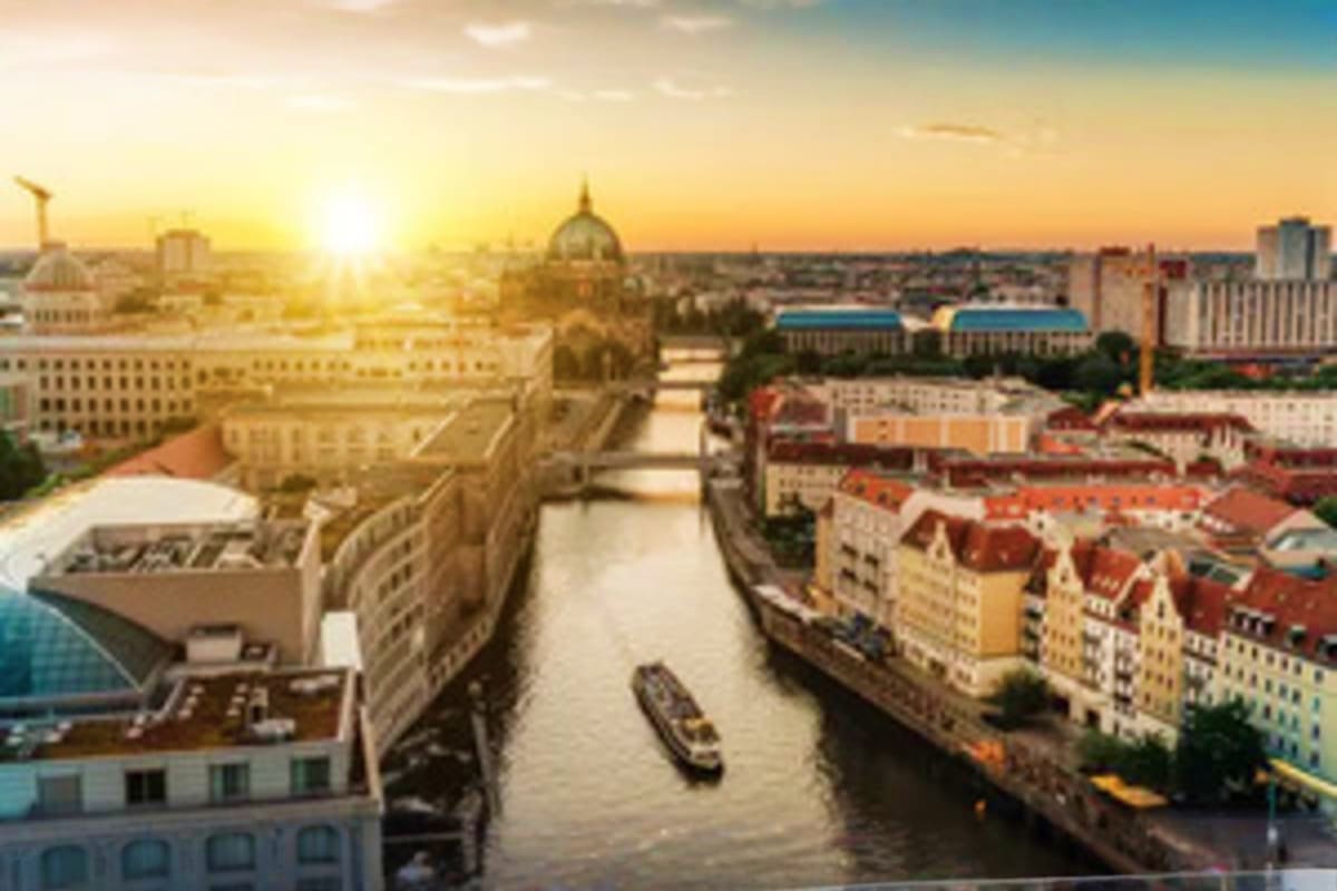 Sunset view of Berlin cityscape with Spree River, historic dome cathedral, and colorful riverside buildings along the waterwa