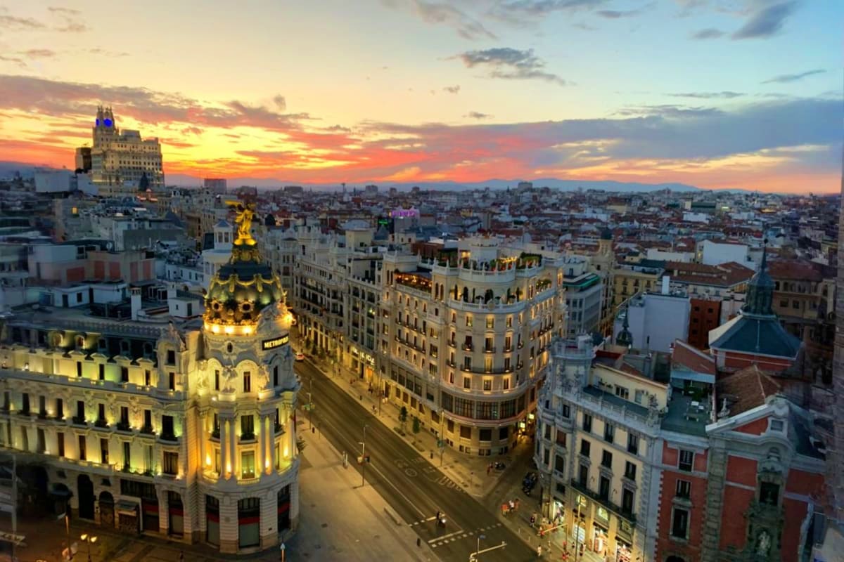 Illuminated historic buildings in Madrid city center at golden hour sunset with ornate architecture and cityscape