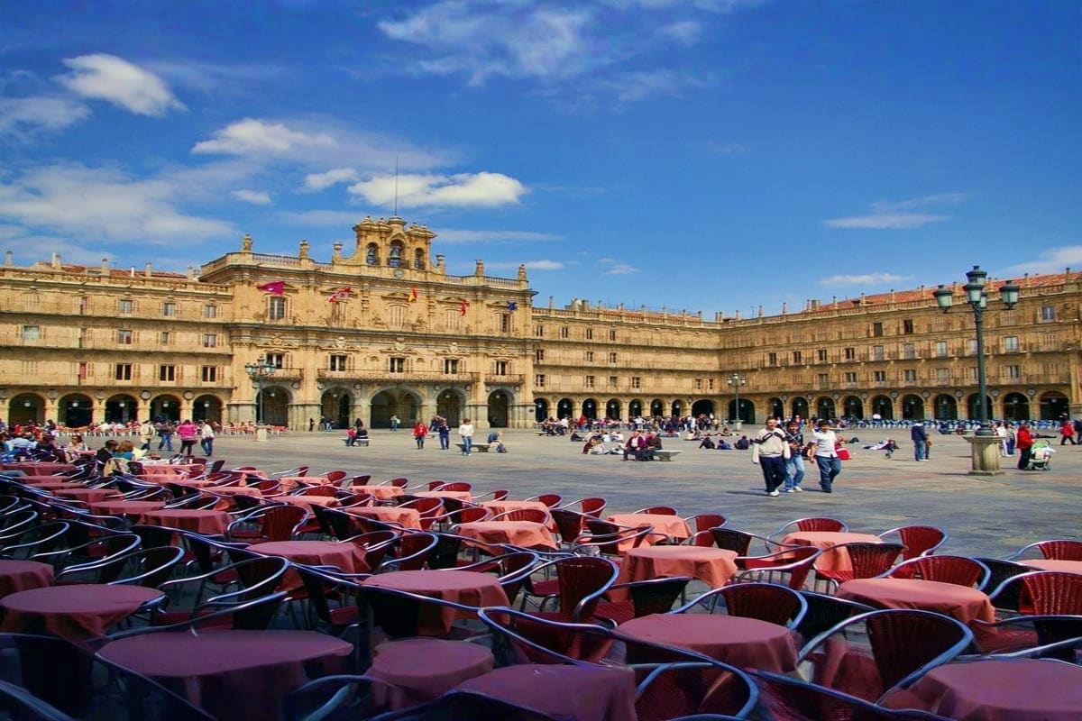 Plaza Mayor in Salamanca, Spain with Renaissance buildings, outdoor café seating, and tourists enjoying the historic square u