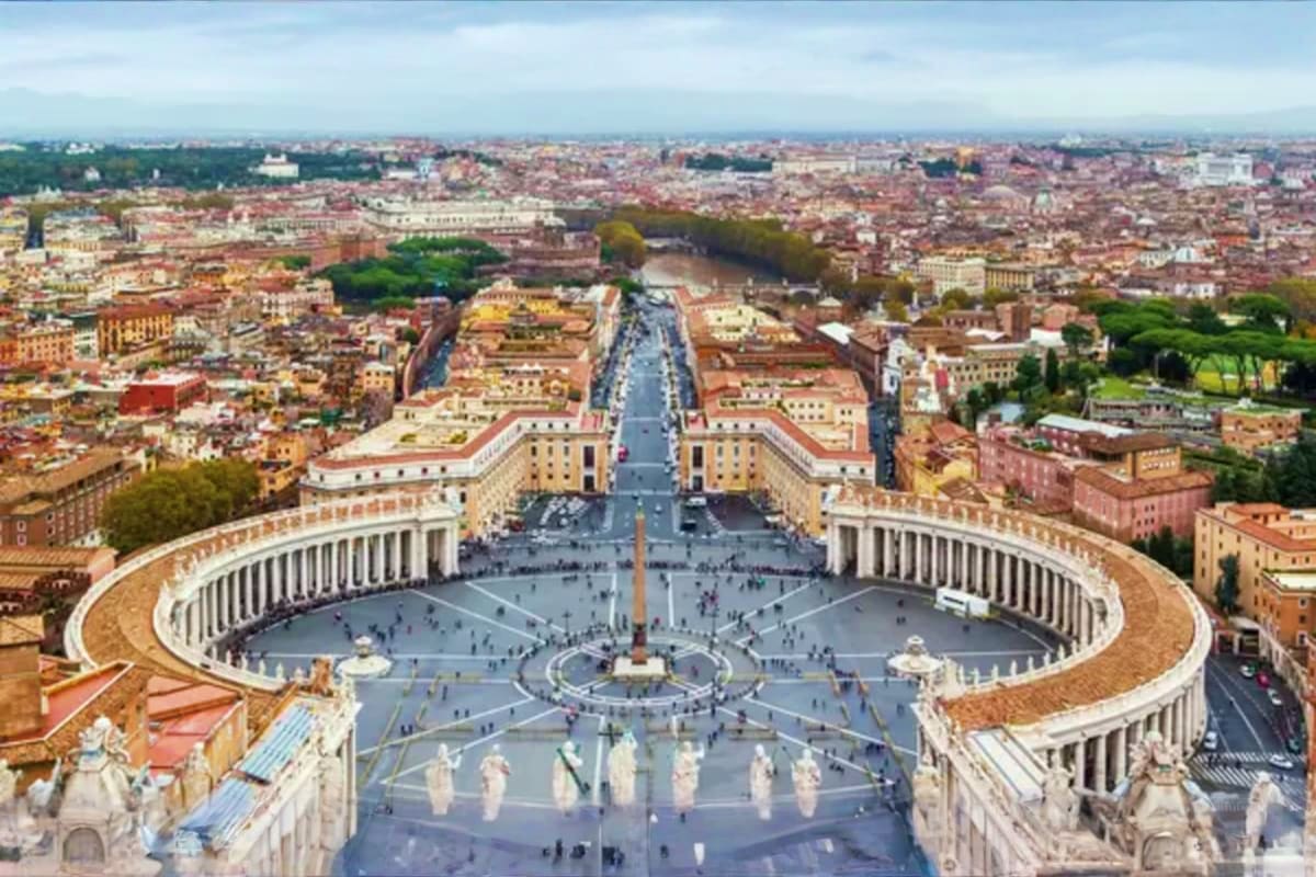 Aerial view of Vatican City's St. Peter's Square with colonnades, obelisk, and Rome cityscape in the background