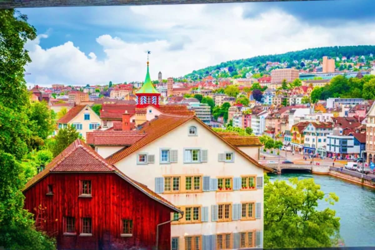 Historic buildings and river in Zurich Switzerland with green hillside and church spire in background