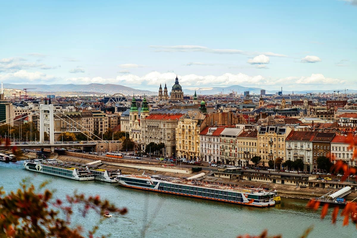 Danube river cruise ships docked in Budapest with St. Stephen's Basilica and Elizabeth Bridge visible in the cityscape