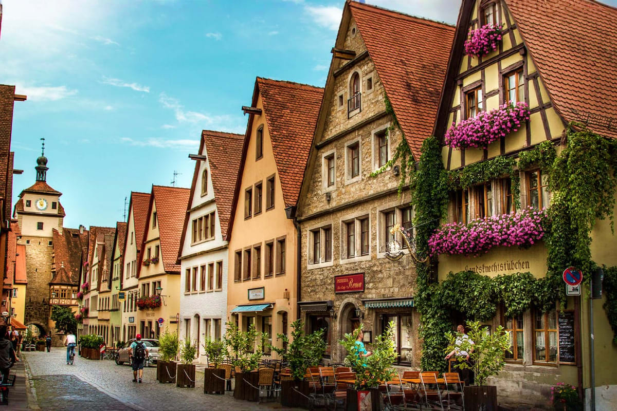 Historic European street with half-timbered buildings, terracotta roofs, and a church tower in a charming old town square